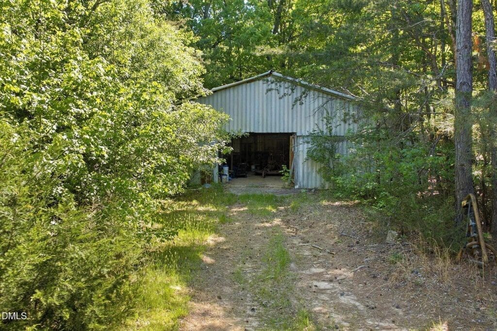 Metal storage barn in wooded area with dirt path